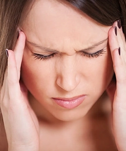 Woman holding head in pain from chronic migraine, treated with botulinum to reduce episodes