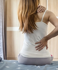 Woman holding her back in discomfort due to muscle contractures, treated for better mobility