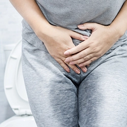 Person clutching lower abdomen, showing signs of overactive bladder treated with botulinum care