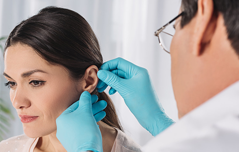Doctor evaluating torn earlobe for repair surgery at Sushruta near Gandhipuram Coimbatore